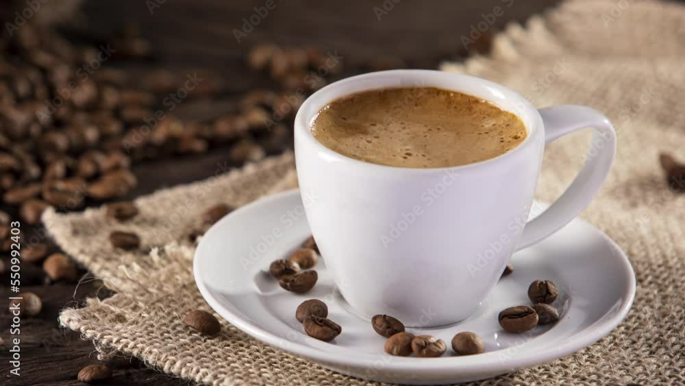 Cup of Espresso in Close. Slow Motion Movement. coffee cup on a jute fabric and some scattered coffee beans Cup of Espresso in Close. Slow Motion Movement. coffee cup on a jute fabric and some scattered coffee beans