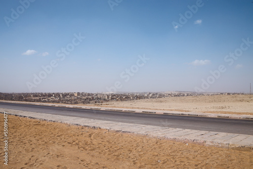 The panorama of a road on desert area near the famous Giza pyramids, Egypt.