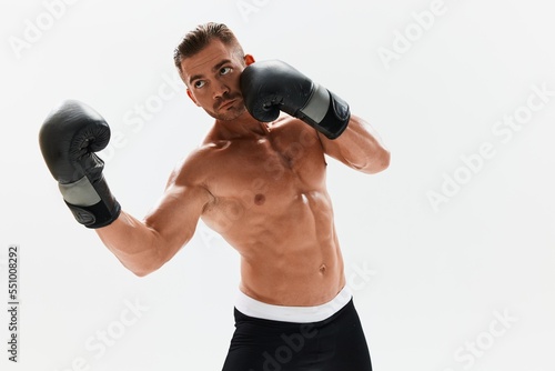 Man athletic bodybuilder poses in boxing gloves with nude torso abs in full-length background, boxing and martial arts. Advertising, sports, active lifestyle, competition, challenge concept. 