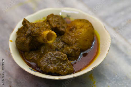 mutton curry and potato served in a bowl. the dish cooked in traditional indian style. spicy red gravy and potato is accompanied.photo taken with selective focus. photo