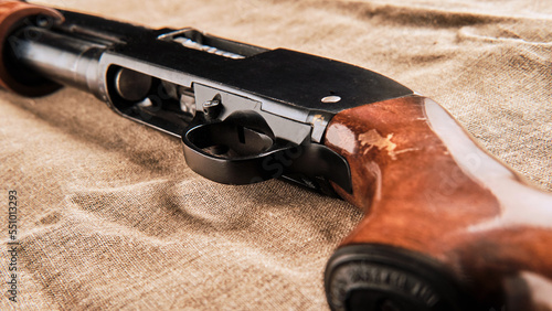 a pump-action shotgun lies on a coarse cloth photo