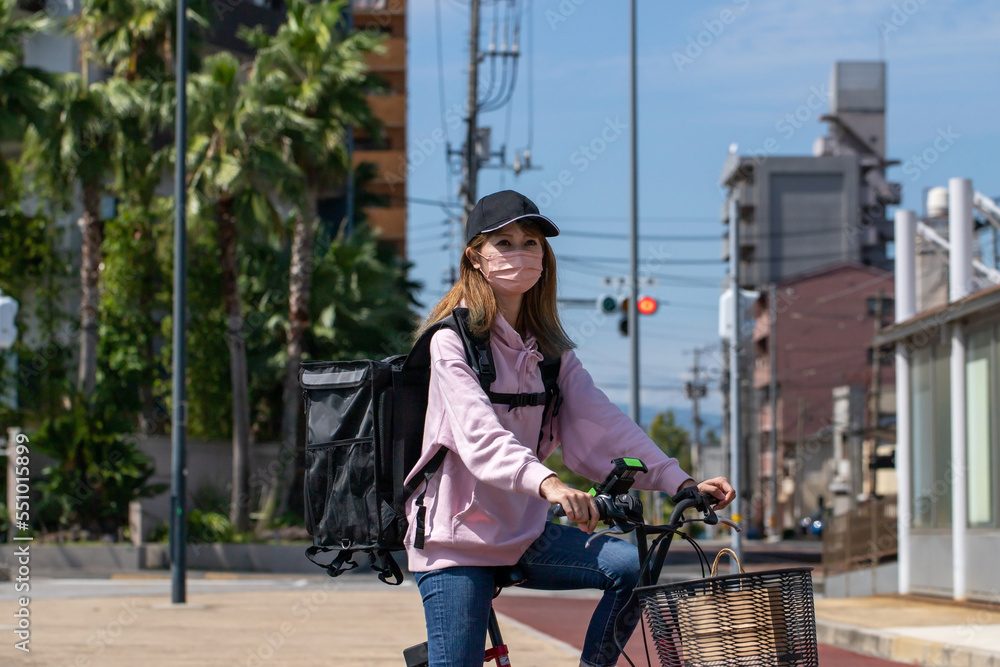 自転車で配達するフードデリバリーの女性