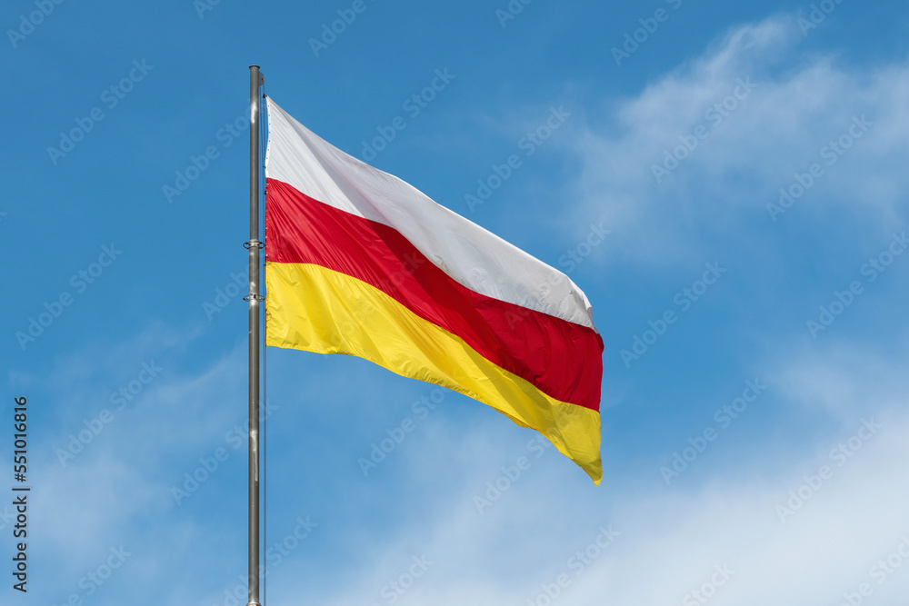 North Ossetian flag on the background of blue sky on sunny day. Vladikavkaz, North Ossetia, Russia. North Ossetian flag on the background of blue sky on sunny day. Vladikavkaz, North Ossetia, Russia.