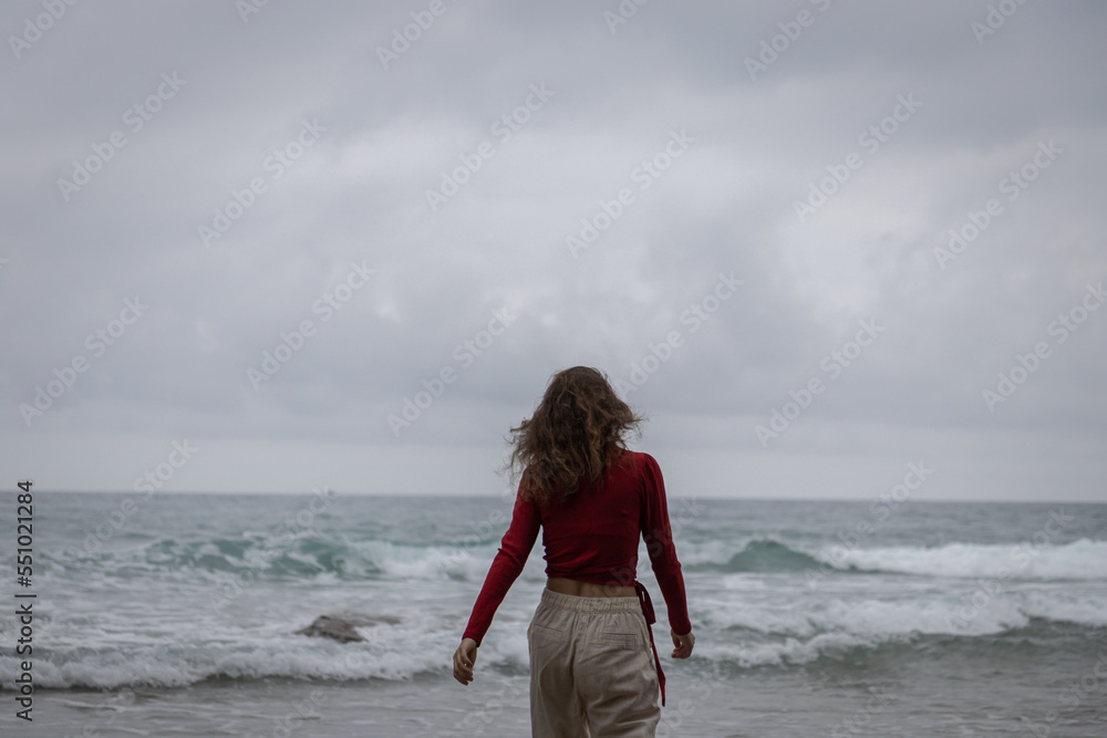 Young caucasian woman on the Ocean Beach. Girl outdoor portrait on a sea background, brunette in red shirt, naturalness Young caucasian woman on the Ocean Beach. Girl outdoor portrait on a sea background, brunette in red shirt, naturalness