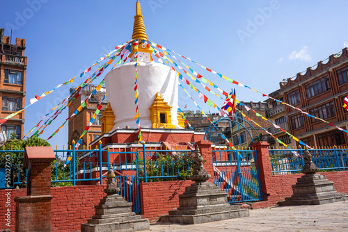 Fototapeta Large white stupa with golden top and many colorful prayer flags in a courtyard in Kathmandu Nepal