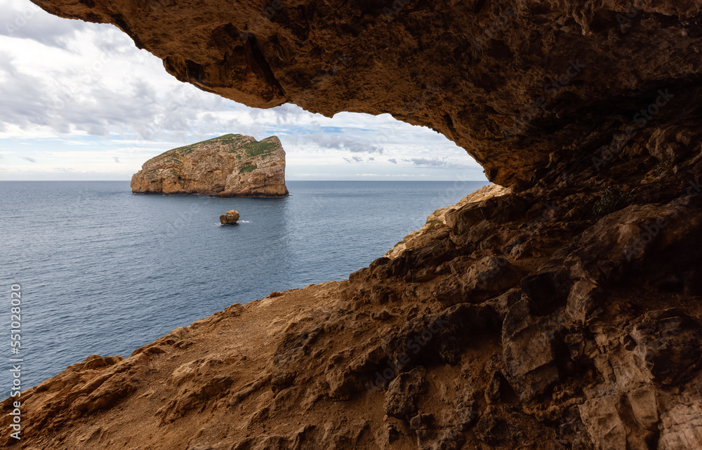 Cave on Rocky Coast with Cliffs on the Mediterranean Sea. Cloudy Sky. Regional Natural Park of Porto Conte, Sardinia, Italy. Nature Background.