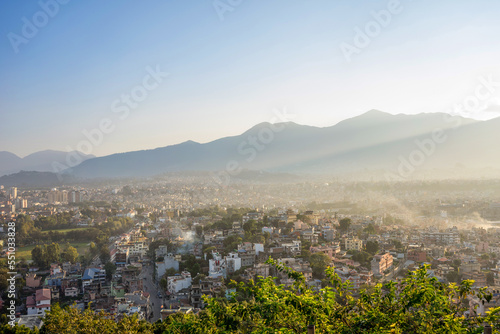 Panoramic view of Kathmandu valley Neoal from a hill at sunset. Blue sky as copy space. A light golden glow lies over the houses of the city photo