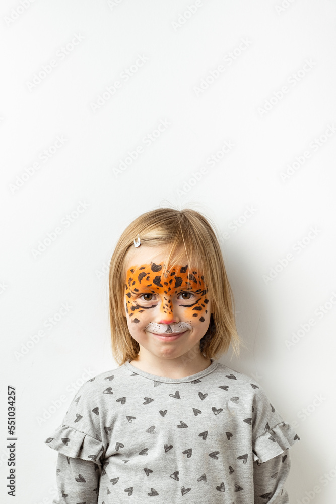 Cute little caucasian girl with tiger face painting on the white background. Close up portrait of little kid with face-painting. Year of a tiger. Happy smiling girl Cute little caucasian girl with tiger face painting on the white background. Close up portrait of little kid with face-painting. Year of a tiger. Happy smiling girl