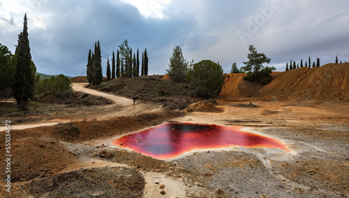 Canvas Print Unrecognizable man walking  near a Lake with red polluted toxic water