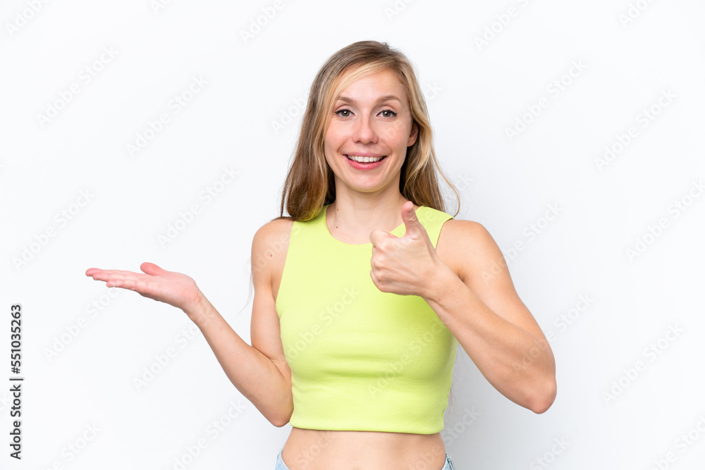 Fototapeta premium Young caucasian woman isolated on white background holding copyspace imaginary on the palm to insert an ad and with thumbs up