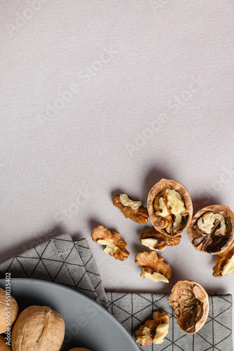  Some of whole and broken walnuts with shell on napkin on gray background top view with copy space