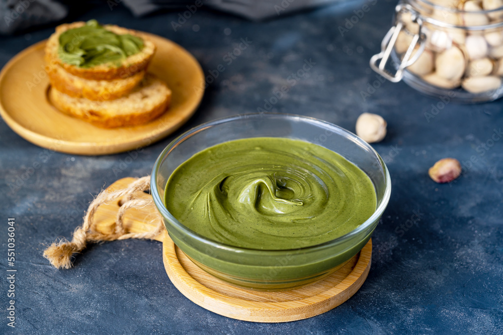 Pistachio cream in bowl with crostini on dark stone background Pistachio cream in bowl with crostini on dark stone background