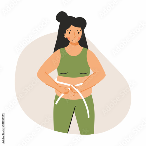 A sad woman measures her stomach with a centimeter tape. The problem with being overweight. Fatness.