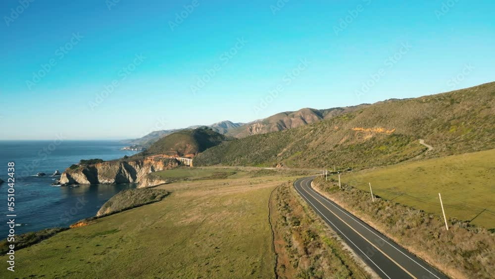 Aerial view of the winding road on the edge of a coastal cliff. Cinematic setting around scenic drive with azure waters of Pacific Ocean in the background. High quality 4k footage Aerial view of the winding road on the edge of a coastal cliff. Cinematic setting around scenic drive with azure waters of Pacific Ocean in the background. High quality 4k footage