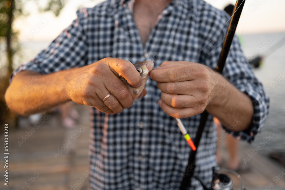 Close-up of a man holding a fishing rod and fish, sport fishing.
