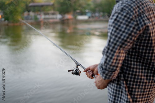 Fisherman with rod, spinning reel on the river bank. Sunrise. Summer morning. rural getaway.