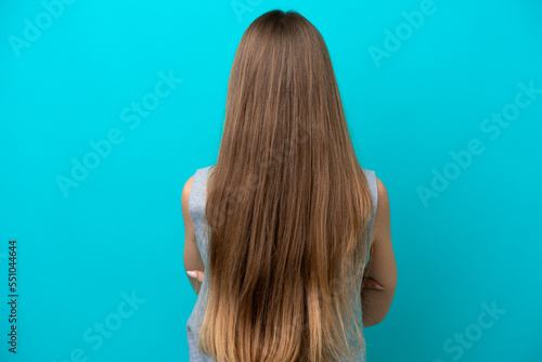 Young Lithuanian woman isolated on blue background in back position