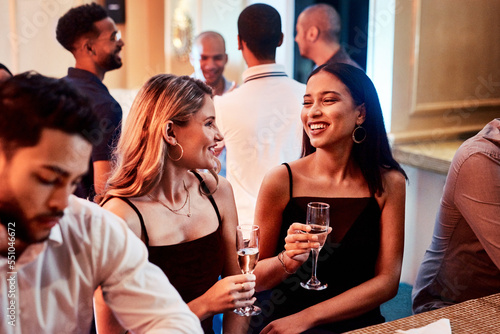 Friends, party and alcohol drink, champagne and event at restaurant, happy smile and crowd conversation at night. People talking, drinking and happiness at club together talking, fun and social