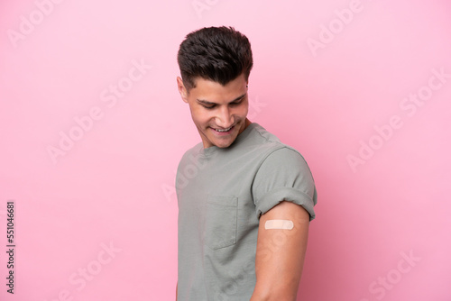 Young caucasian man wearing band-aids isolated on pink background with happy expression