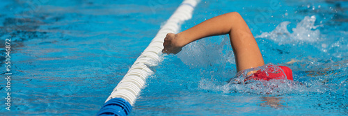 Swimmer child athlete swimming in pool lanes doing a crawl lap. Sport activities for children