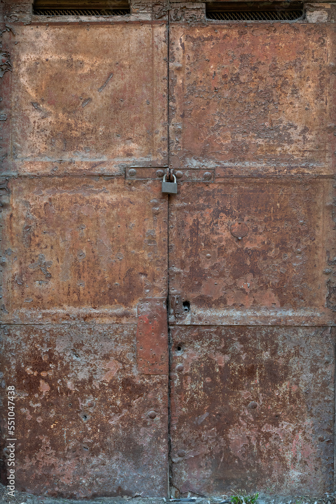 Ancient rusty iron door closed by a padlock Ancient rusty iron door closed by a padlock