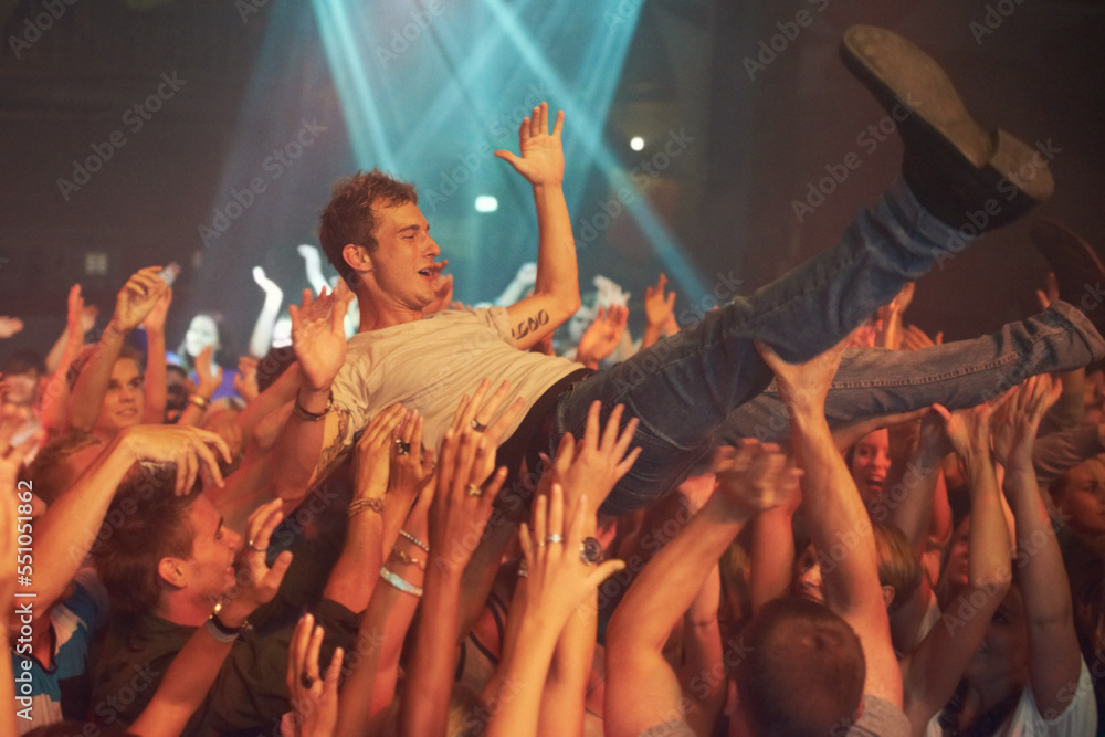 Music, party and crowd surfing with man at concert for rock, celebration and festival. Energy, light and dance with audience listening to live band show performance at disco, summer break and dj