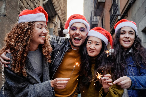 Happy young diverse people having fun celebrating with bengal sparkler in winter time - Christmas and friends concept - Focus on gay transgender man