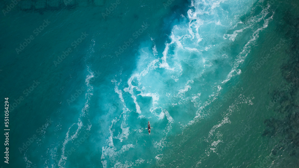 Top view  of a man paddles a kayak in raging sea water