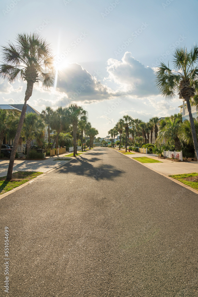 Sun behind the clouds above the asphalt street in a residential area at Destin, Florida