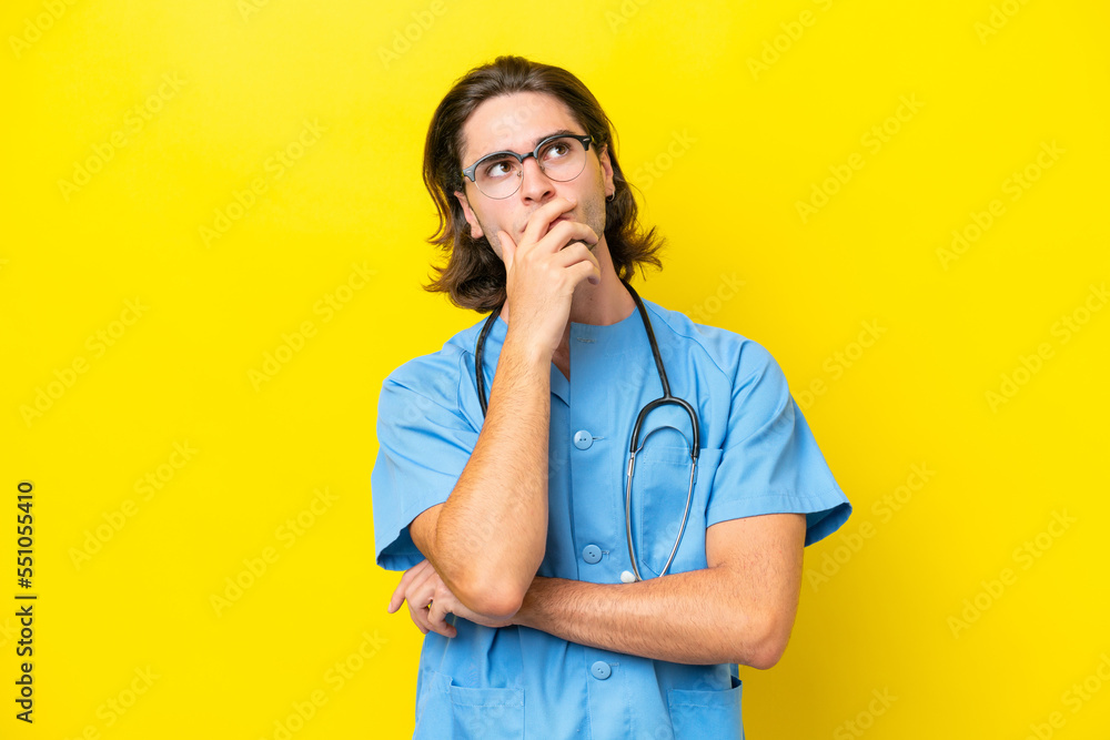 Young surgeon caucasian man isolated on yellow background having doubts and with confuse face expression Young surgeon caucasian man isolated on yellow background having doubts and with confuse face expression