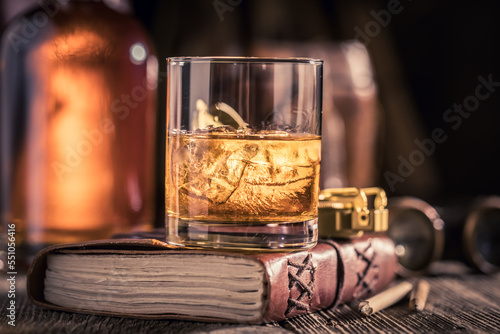 Noble and aged whisky on rock with journal and compass.