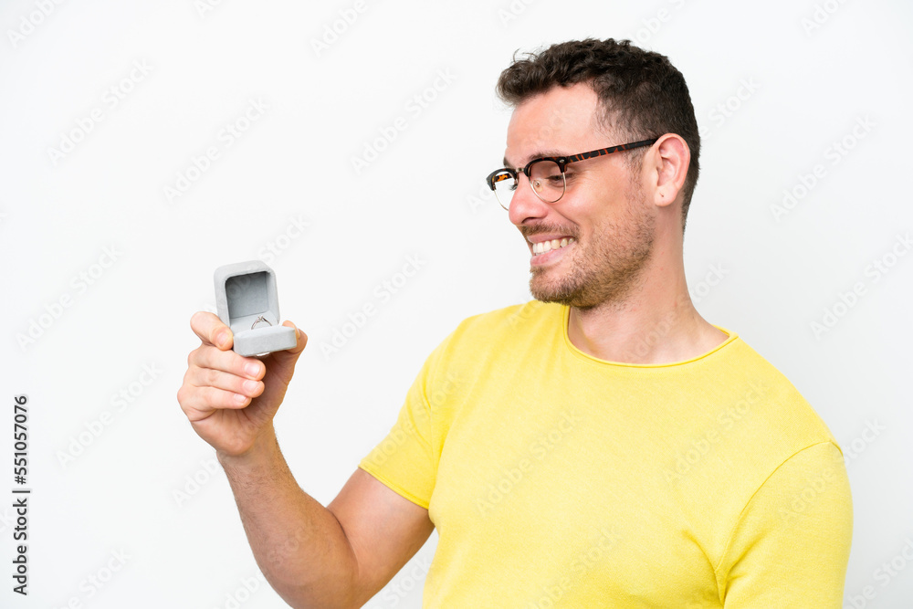 Young caucasian man holding a engagement ring isolated on white background with happy expression Young caucasian man holding a engagement ring isolated on white background with happy expression