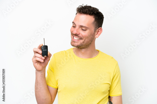 Young man holding car keys isolated on white background with happy expression