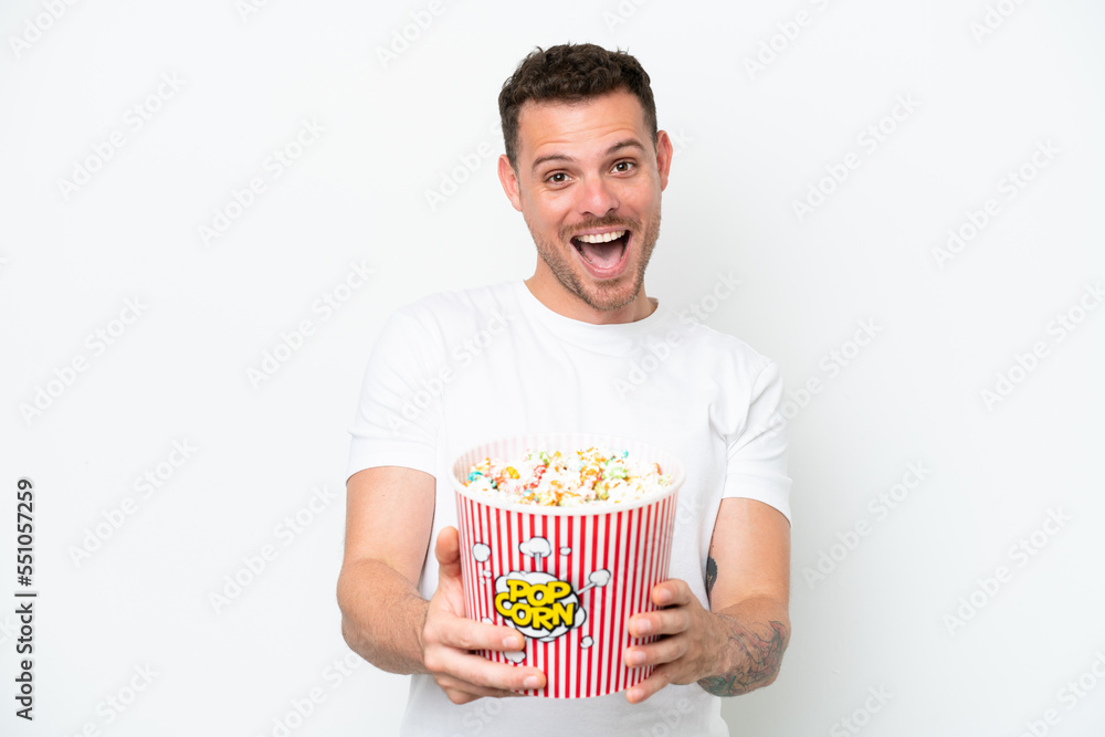 Young caucasian handsome man isolated on white background holding a big bucket of popcorns Young caucasian handsome man isolated on white background holding a big bucket of popcorns
