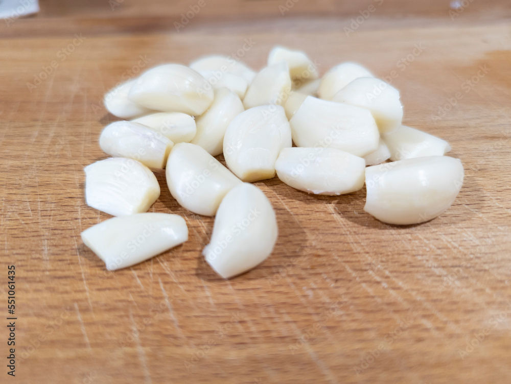 fresh peeled garlic on a cutting board in a kitchen