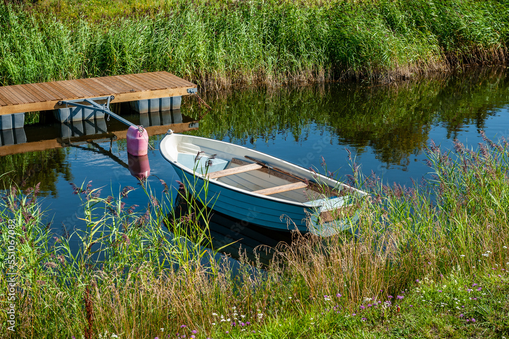 A small fishing boat lies in the wonderful and idyllic backwater. Boat at the pier on a sunny summer day. A small fishing boat lies in the wonderful and idyllic backwater. Boat at the pier on a sunny summer day.