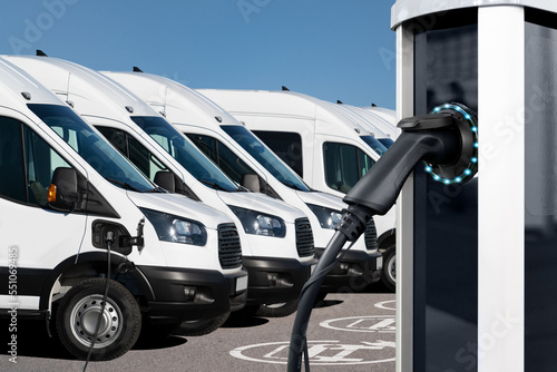 Fotografie, Obraz Electric vehicles charging station on a background of a row of vans