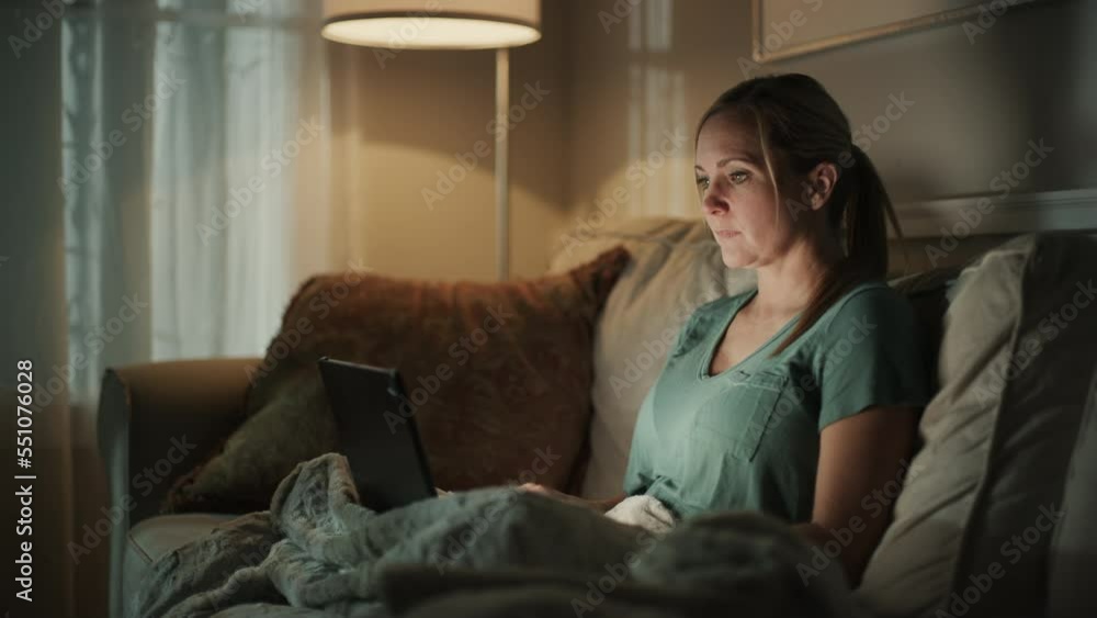Woman sitting on sofa at night typing on laptop / Cedar Hills, Utah, United States Woman sitting on sofa at night typing on laptop / Cedar Hills, Utah, United States