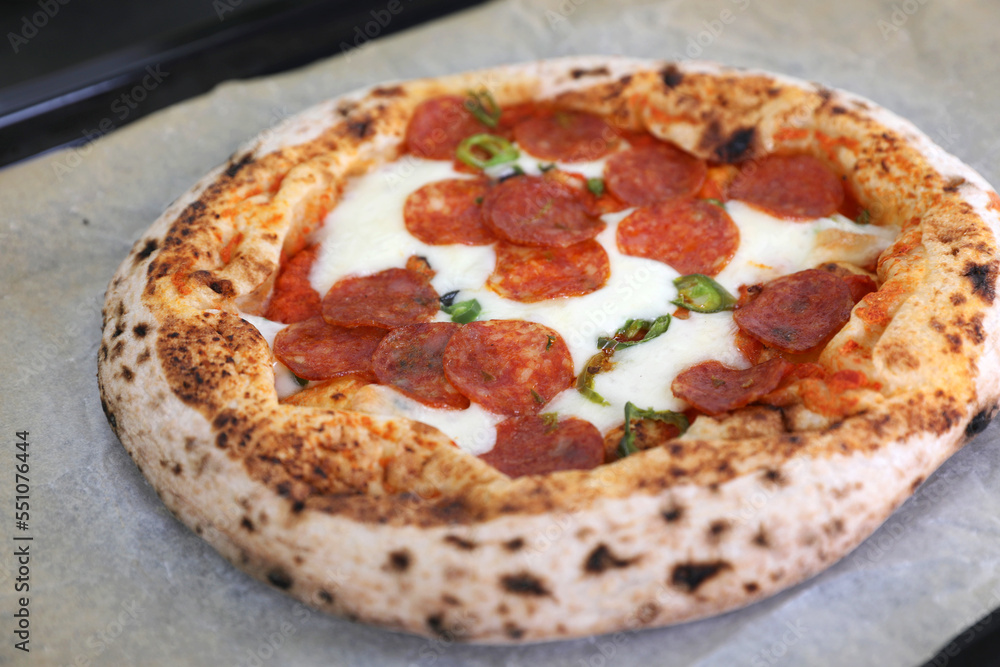 Neapolitan pizza with sausage and jalapeno in the kitchen at home Neapolitan pizza with sausage and jalapeno in the kitchen at home