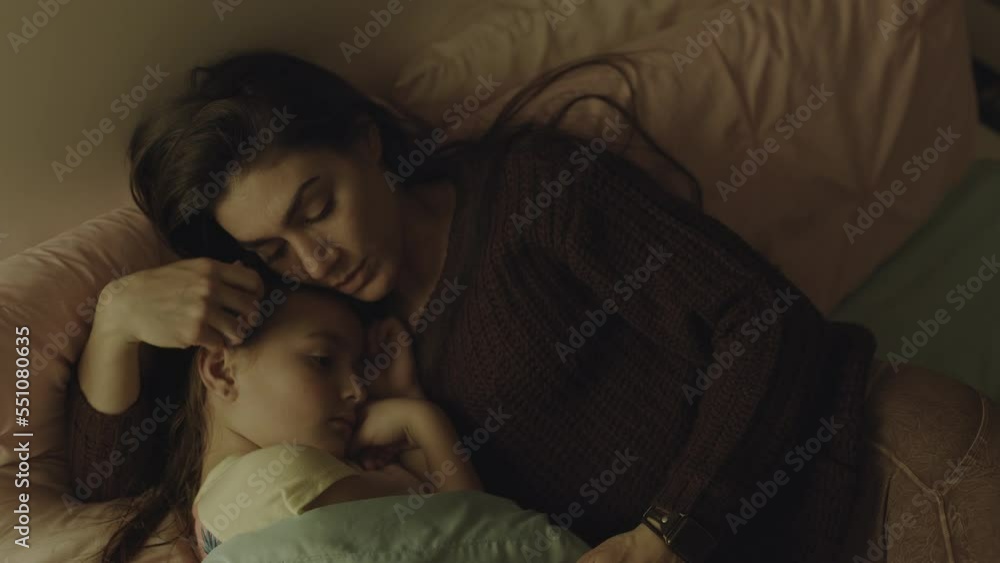 Close up high angle view of mother comforting daughter in bed / South Jordan, Utah, United States Close up high angle view of mother comforting daughter in bed / South Jordan, Utah, United States