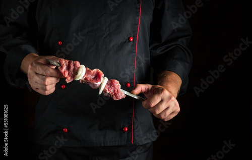 Professional chef holds shish kebab in hands with raw lamb meat. Asian national cuisine