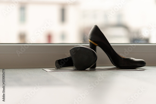 Black high heel pumps in front of a window and on a light floor
