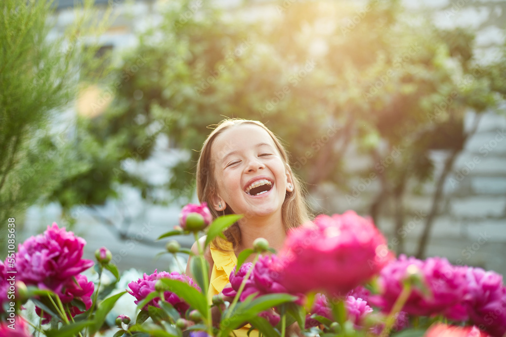 Happy little girl with braces in the garden in bushes of peonies Happy little girl with braces in the garden in bushes of peonies