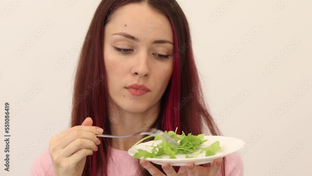 Young woman with an eating disorder eats lettuce leaves. Slim girl on a diet. Young woman with an eating disorder eats lettuce leaves. Slim girl on a diet.
