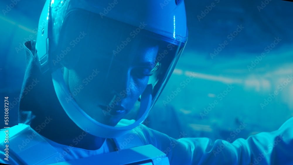 A woman astronaut in a space suit aboard the orbital station. A young female cosmonaut pilots a spaceship. Galactic travel and science concept.