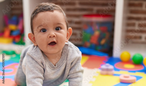 Adorable hispanic baby crawling on floor at kindergarten