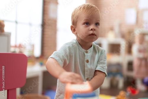 Adorable toddler playing with truck toy standing at kindergarten