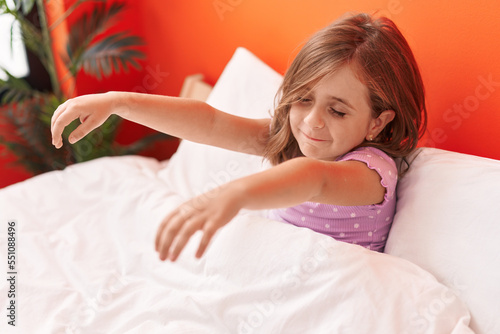 Foto Adorable hispanic girl somnambulist sleepwalking sitting on bed at bedroom