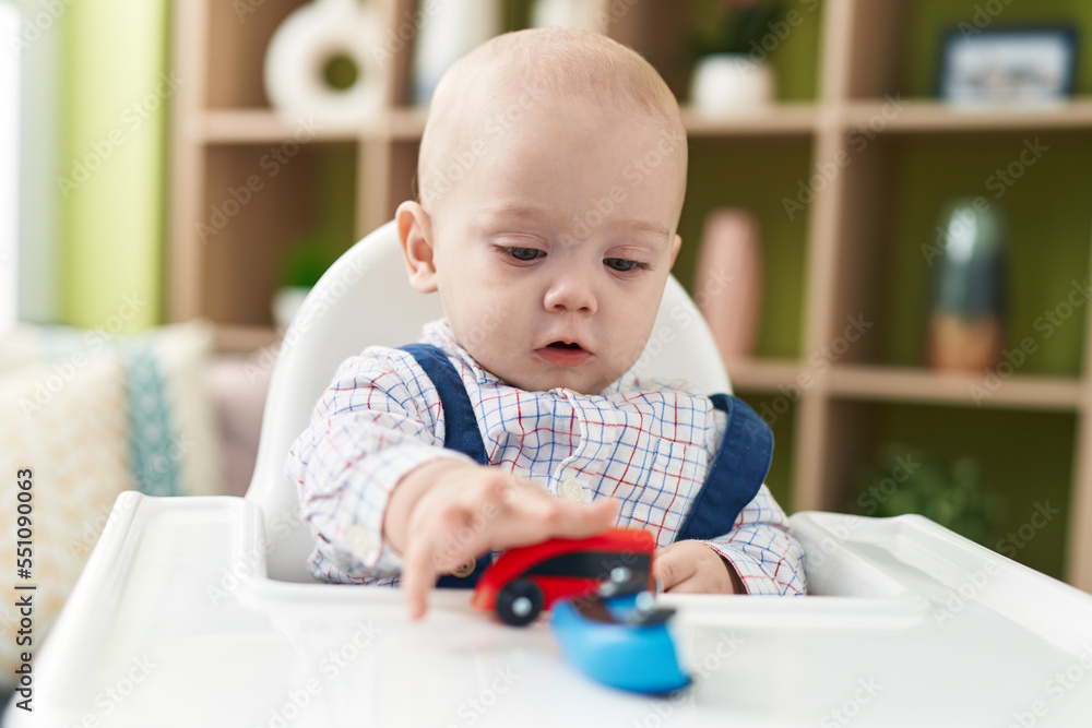 Adorable caucasian baby palying with cars toy sitting on highchair at home Adorable caucasian baby palying with cars toy sitting on highchair at home