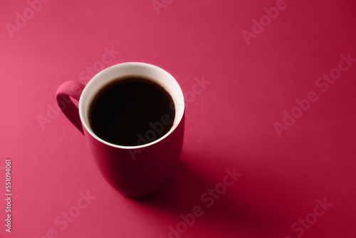 Coffee in viva magenta cup on monochrome background. Close up. Copy space. Trending color of 2023 - Viva Magenta.